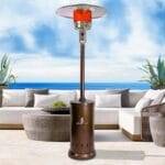 Bronze Verona heater outside in front of sofas with beach in the distance