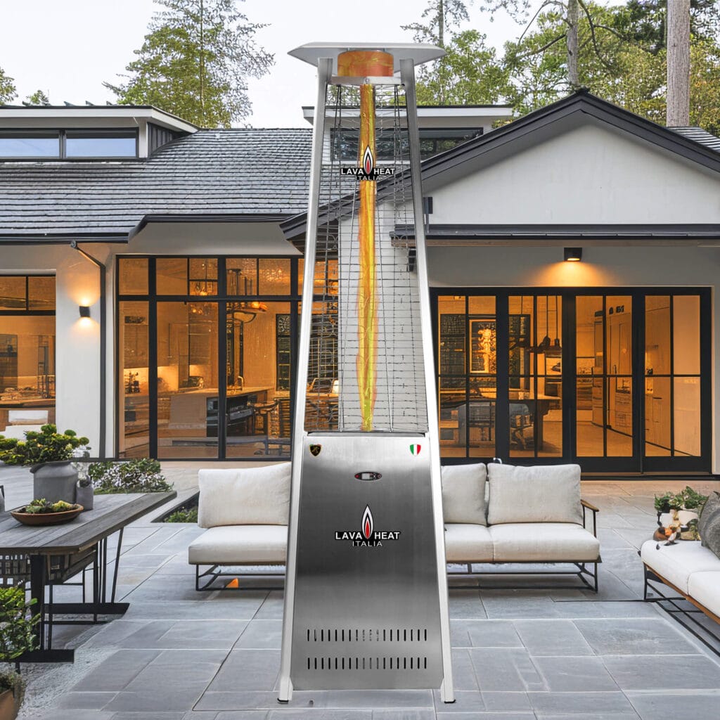 A silver The 2G heater standing outdoors in front of sofas.